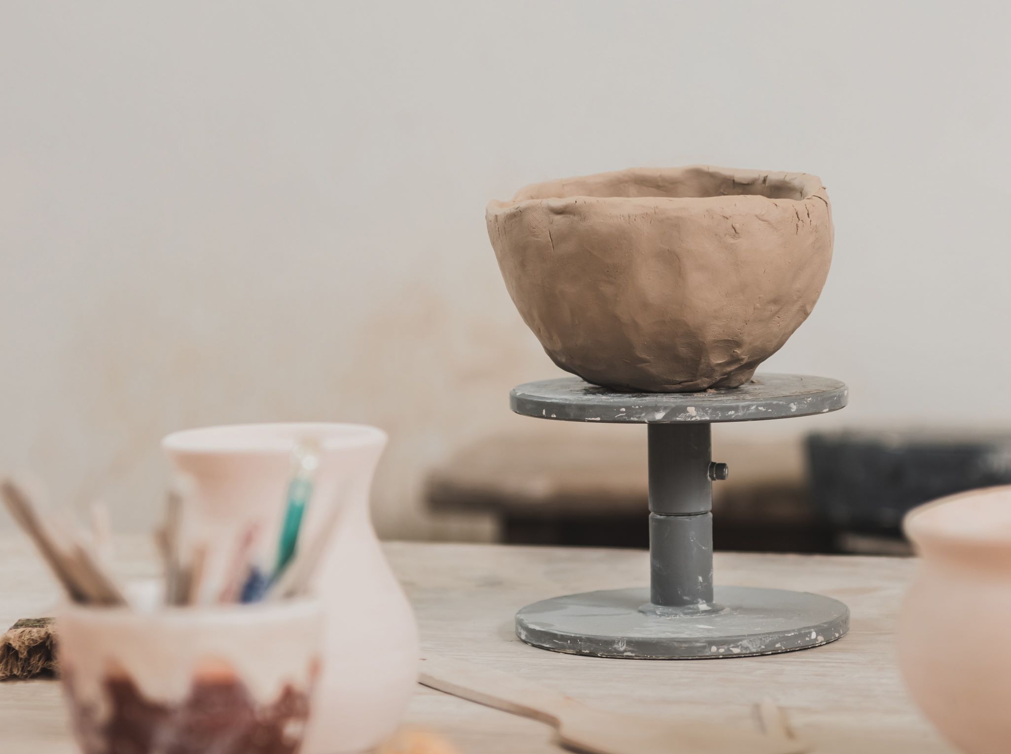 Sculpted-Clay-Bowl-On-Wooden-Table-In-Pottery-Art