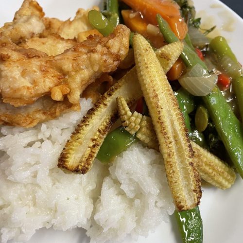 A Plate Of White Rice Topped With Crispy Fried Chicken, Stir-Fried Vegetables Including Baby Corn, Carrots, Snap Peas, And Green Beans. The Dish Is Vibrant With A Mix Of Textures And Colors. A Plate Of White Rice Topped With Crispy Fried Chicken, Stir-Fried Vegetables Including Baby Corn, Carrots, Snap Peas, And Green Beans. The Dish Is Vibrant With A Mix Of Textures And Colors.