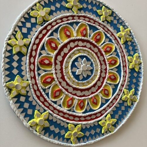 Colorful Circular Decorative Design On A Wall, Featuring Concentric Rings With Floral Patterns In Yellow, Red, And White On A Blue Background. The Outer Edge Is Adorned With Yellow Flowers. Colorful Circular Decorative Design On A Wall, Featuring Concentric Rings With Floral Patterns In Yellow, Red, And White On A Blue Background. The Outer Edge Is Adorned With Yellow Flowers.